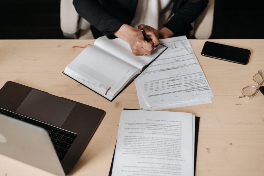 Deux entrepreneurs congolais signant un contrat commercial dans un bureau à Kinshasa, RDC, avec des documents juridiques et un stylo.